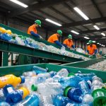 A recycling plant with conveyor belts sorting and crushing plastic bottles, with workers transforming the plastic into fashionable clothing and accessories